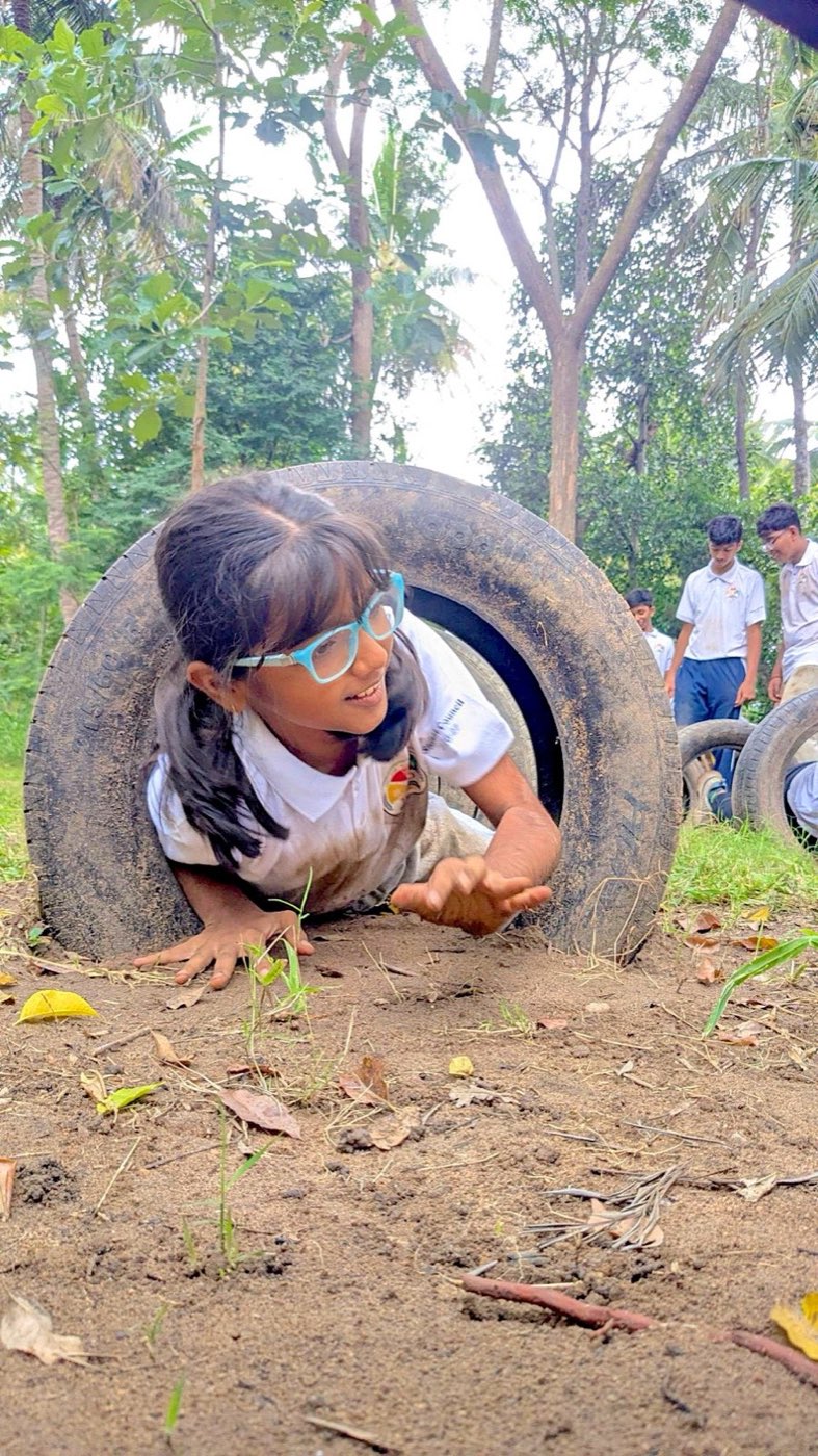 A student crawling through a tyre in an obstacle course