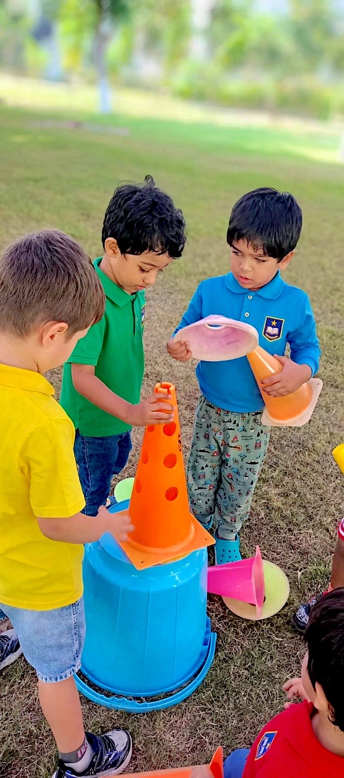 Young children stacking cones together on a lawn